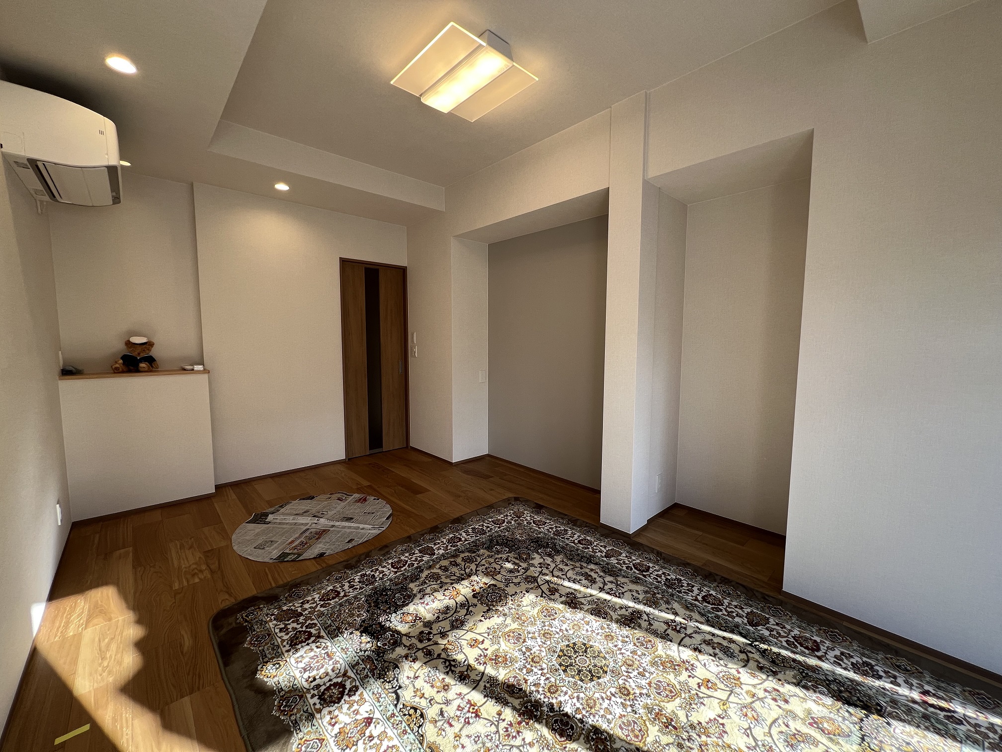 玄関改修と合わせた洋間のリフォーム。折上げ天井で開放感を出し、グレーのアクセントクロスでモダンに仕上げた内装デザイン。